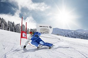 Skifahrer fährt mit blauem Skianzug eng an einem Riesentorlauftor vorbei, im Hintergrund ein Starthaus mit der Aufschrift BMW xDrive Cup