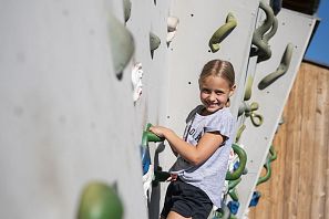Kind klettert an einer Kletterwand.