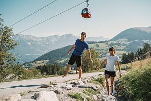 Personen wandern barfuß entlang eines kleinen Flusses.