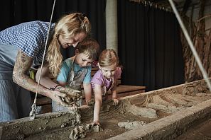 Kinder formen mit einer Helferin etwas aus Ton.