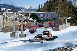 Visualisierung der Choralmbahn 2008: Liftstation mit roten Gondeln und grünem Dach, im Vordergrund eine Pistenraupe bei der Präparierung der Schneefläche