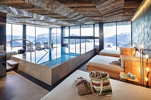 Moderner Spa-Bereich mit Indoor-Pool, Panoramafenstern und gemütlichen Ruhebetten mit Blick auf die verschneiten Alpen