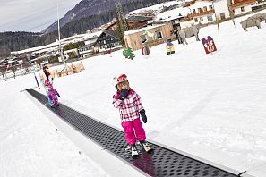 Zwei Kinder stehen mit Ski auf dem Zauberteppich am Übungsgelände auf der Hexenwiese