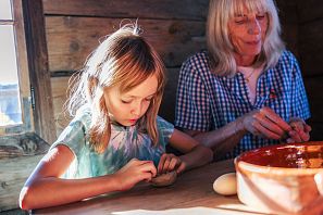 Kind mit Mutter am Töpfern in einer Holzhütte in der Hexerei Hexenwasser in Söll