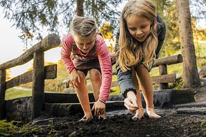 Kinder suchen Regenwürmer in der Erde.
