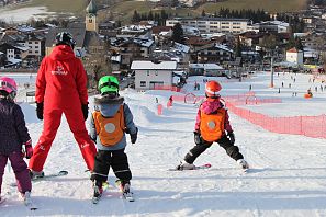 Kinder lernen Skifahren mit einem Skilehrer.