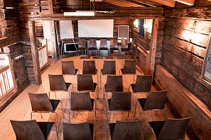 Binnenaanzicht van een seminarruimte met houten lambrisering, zitplaatsen in rijen, scherm en presentatietechniek in een rustieke berghut aan de Filzalmsee.
