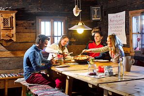 Freunde essen zusammen in einer urigen Almhütte.