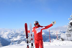 Motivierter Skilehrer mit Ski in der Hand am Gipfel.