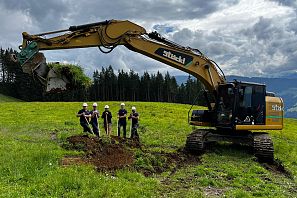 Gelber Bagger und Arbeiter mit5 Schaufeln.