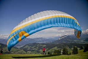 Großer Paragleiter in blau, gelb, weiß und grauer Farme kurz vor dem Abflug