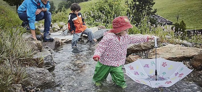 Kinder spielen bei Regen im Wasser.