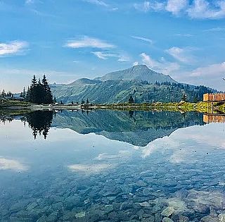 Ausblick auf einen Berg direkt am Ufer eines kristallklaren Sees.