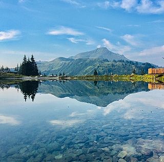 Ausblick auf einen Berg direkt am Ufer eines kristallklaren Sees.
