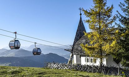 Kapelle mit Ausblick auf Berge und Gondeln.