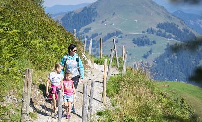 Mutter mit zwei Kindern beim wandern in der Natur.