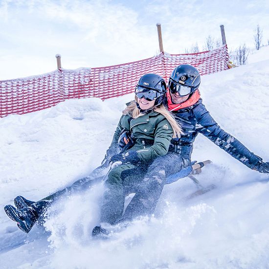 Zwei Rodler am Schlitten auf der Astberg Rodelbahn Going am Tag in der SkiWelt