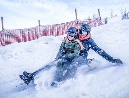 Zwei Rodler am Schlitten auf der Astberg Rodelbahn Going am Tag in der SkiWelt