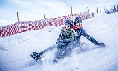 Zwei Rodler am Schlitten auf der Astberg Rodelbahn Going am Tag in der SkiWelt