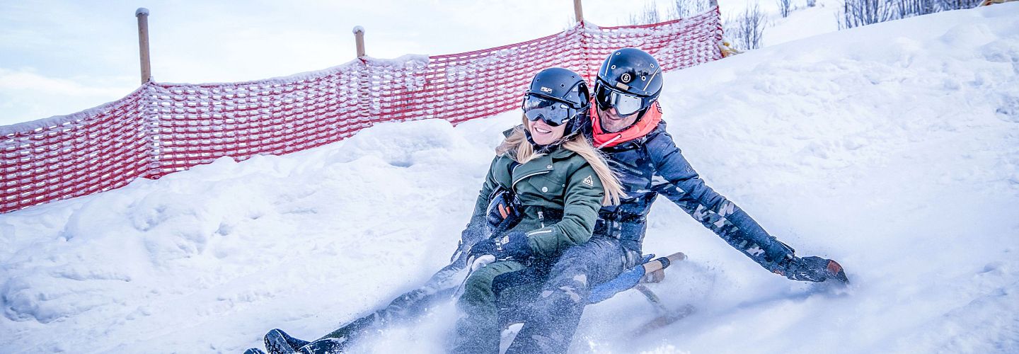 Zwei Rodler am Schlitten auf der Astberg Rodelbahn Going am Tag in der SkiWelt