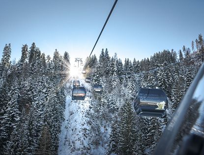 Gondeln vor verschneiten Bäumen.
