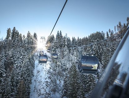 Gondeln vor verschneiten Bäumen.