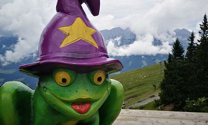 Ellmi der Frosch aus Holz vor bewölktem Himmel.