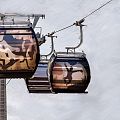 Gondeln einer Seilbahn mit Hans im Glück Aufdruck fahren über eine verschneite Winterlandschaft mit nebelverhangenem Himmel