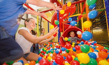 Kinder spielen in einem bunten Bällebad.