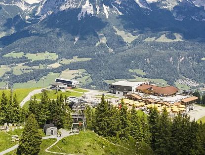 Luftaufnahme der Gipfelstation Hartkaiser in ellmau mit Bergrestaurant, Sessellift, Ellmis Zauberwelt und umliegender Alpenlandschaft.