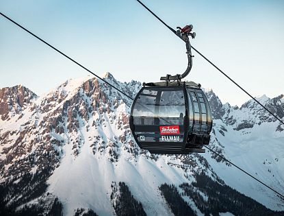 Schwarze Gondel Hartkaiserbahn in Ellmau mit dem verschneiten Wilden Kaiser im Hintergrund