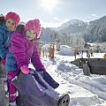 Kinder sitzen im Winter auf einem Holzschwein.