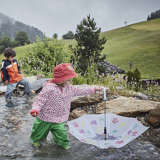 Kinder spielen bei Regen im Wasser.