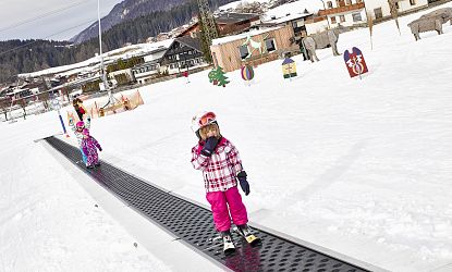Zwei Kinder stehen mit Ski auf dem Zauberteppich am Übungsgelände auf der Hexenwiese