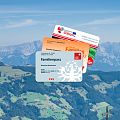 Familienpässe aus Tirol, Südtirol und Bayern vor imposanter Bergkulisse in der SkiWelt Wilder Kaiser-Brixental. Drei Karten für grenzüberschreitende Familienangebote und ermäßigte Freizeitaktivitäten.