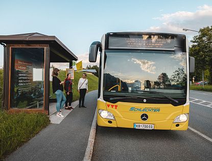 Gelber Bus bei Bushaltestelle, Personen steigen gerade ein im Sommer, ist kostenloser Bus zu Wanderausgangspunkten, Talstationen der Bergbahnen und weiteren Attraktionen für Gäste in der Region Wilder Kaiser
