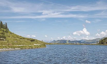 Kreuzjoechlsee in Westendorf inmitten grüner Almwiesen mit Blick auf die umliegenden Alpen bei klarem Sommerwetter.