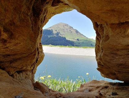 Blick durch Steine auf einen Bergsee.