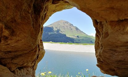Blick durch Steine auf einen Bergsee.