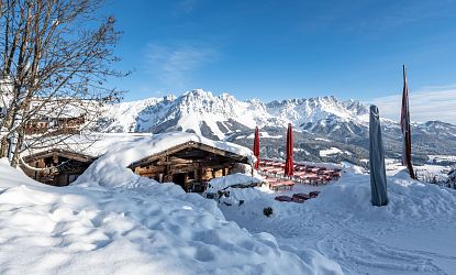 Beschneite Hütte am Berg mit einem Alpenpanorama.