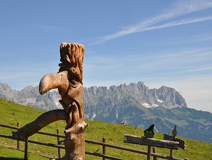 Geschnitzte Figur vor einer Bergkulisse.
