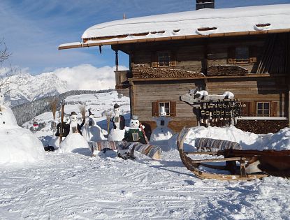 Schneemänner vor der Simonalm im Winter.