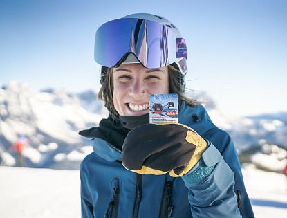 Eine Frau in Skikleidung zeigt ihren Skipass.