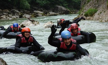 Menschen schwimmen durch einen Bach mit einer Luftmatratze.