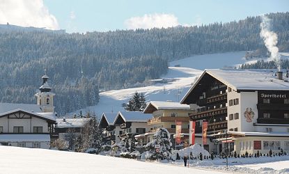 Verschneites Sporthotel Tirolerhof in Itter im Winter, rauch steigt aus dem Schornstein auf