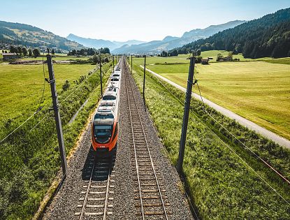 Zug fährt auf Schienen im Sommer.