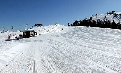 Perfekt präparierte Skipiste mit Übungslift am Brandstadl im sonnigen Skigebiet bei strahlend blauem Himmel.