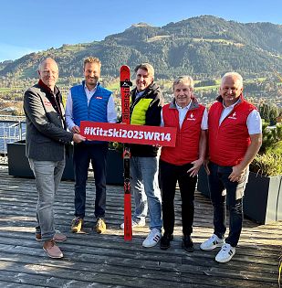 Foto der Menschen die bei dem Weltrekordversuch beteiligt sind. 5 Männer die ein rotes Schild mit der Aufschrift #KitzSki2025WR14 halten