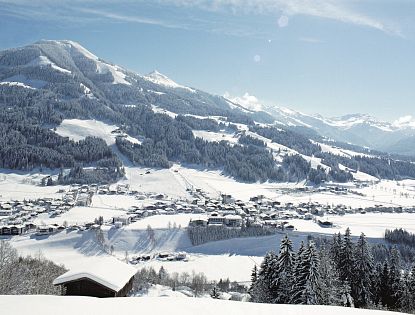 Ortschaft Westendorf verschneit im Winter mit Berglandschaft im Hintergrund