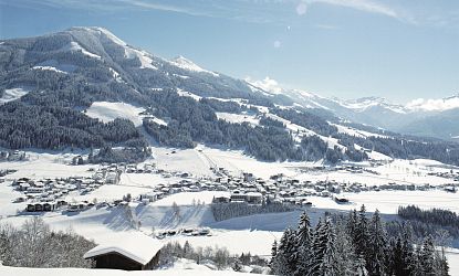 Ortschaft Westendorf verschneit im Winter mit Berglandschaft im Hintergrund